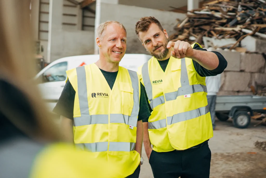 Stefan Locke und Leon Hauser in REVIA-Warnwesten im Gespräch auf dem Betriebsgelände